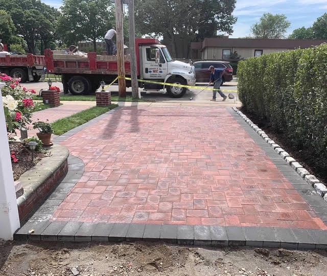 Brick paver driveway installation with Belgium block border