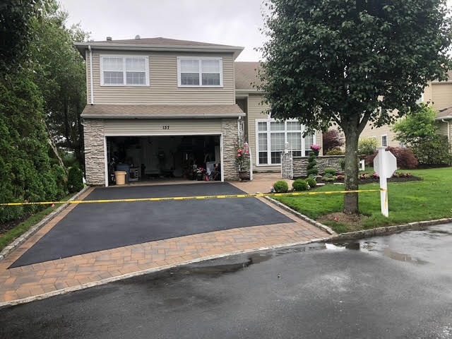 Fresh blacktop driveway with paver apron at the garage