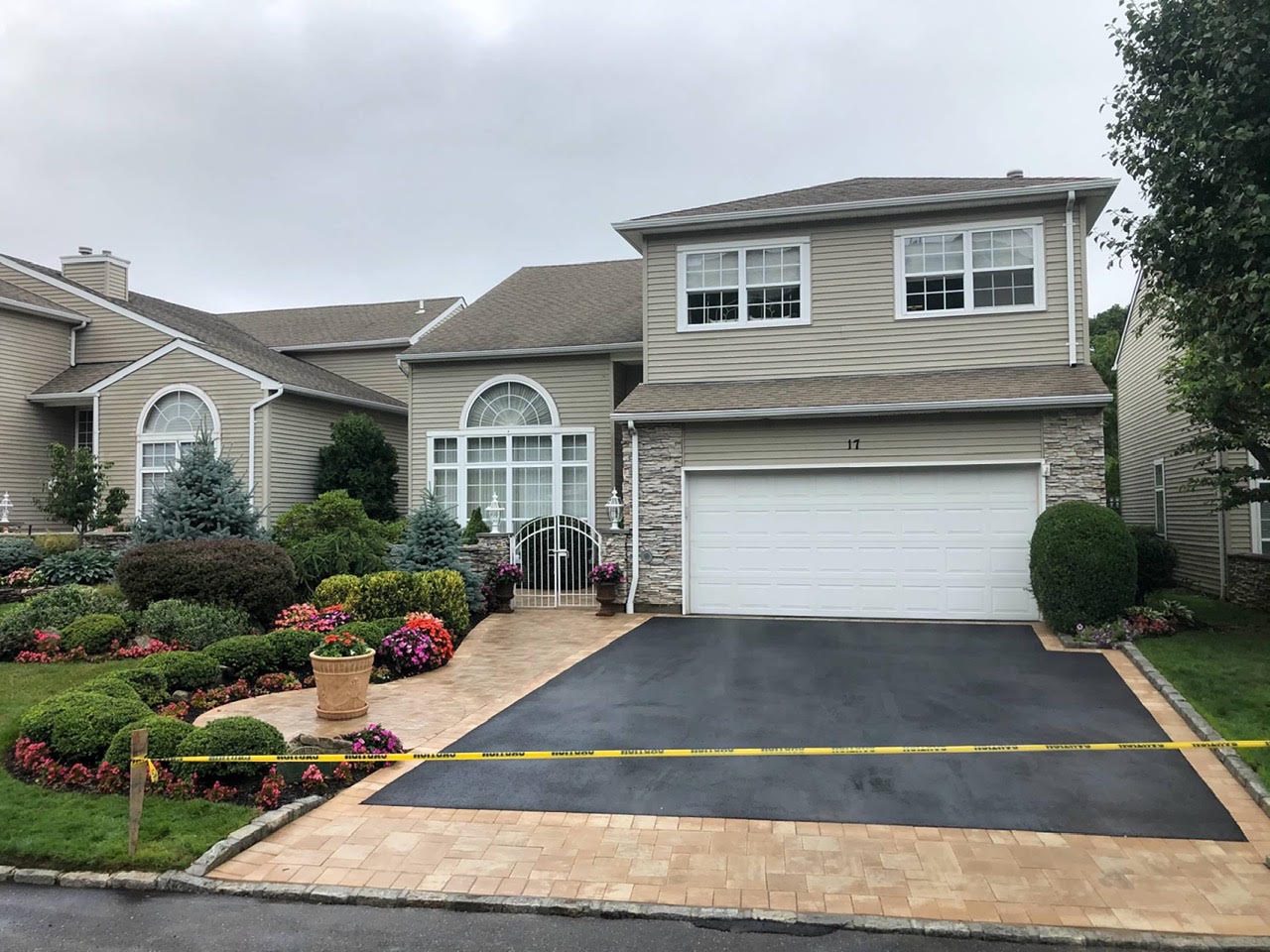 Blacktop driveway with tan paver apron and landscaping