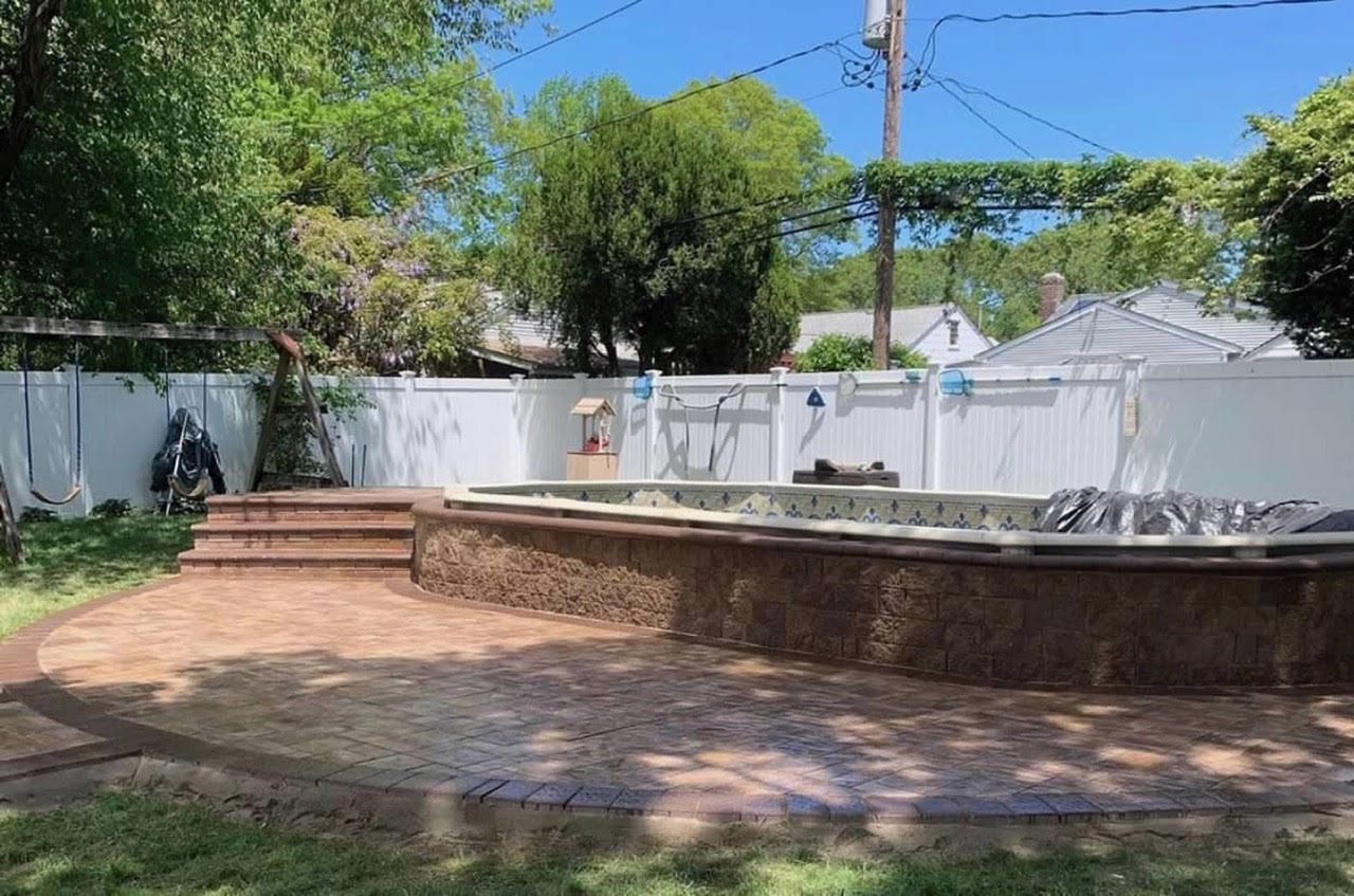 Raised pool with stone block wall and curved brick paver patio deck