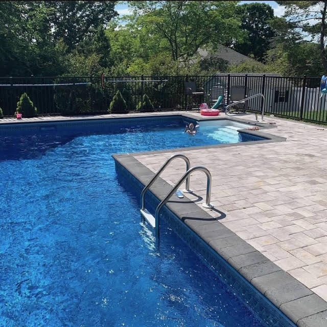 Inground pool with paver deck and coping in a fenced backyard